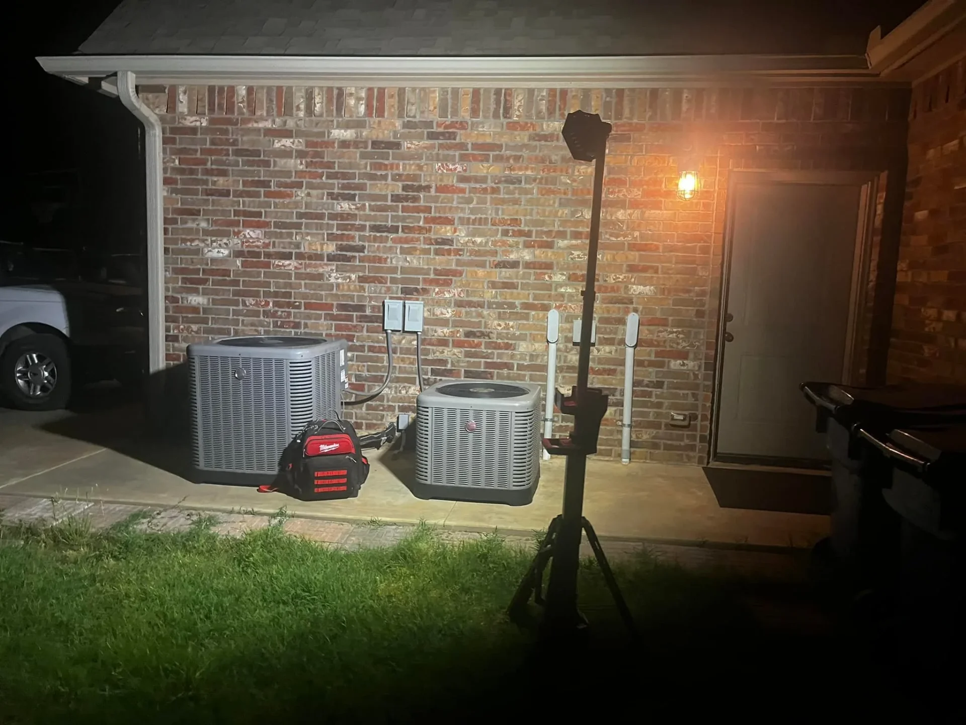 Emergency AC repair at night with tool bag next to HVAC units