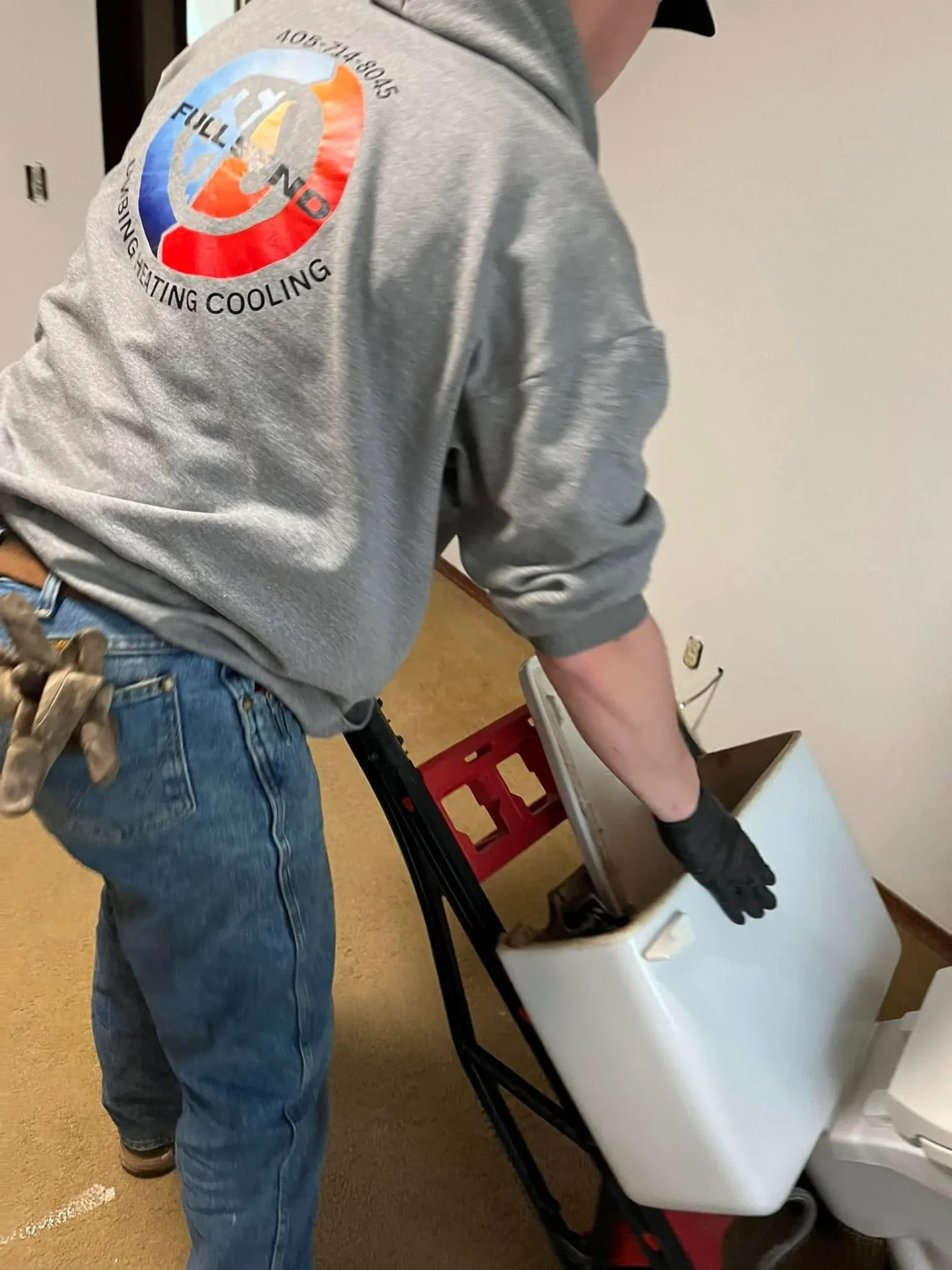 Full Send technician moving toilet tank during installation in Perkins OK